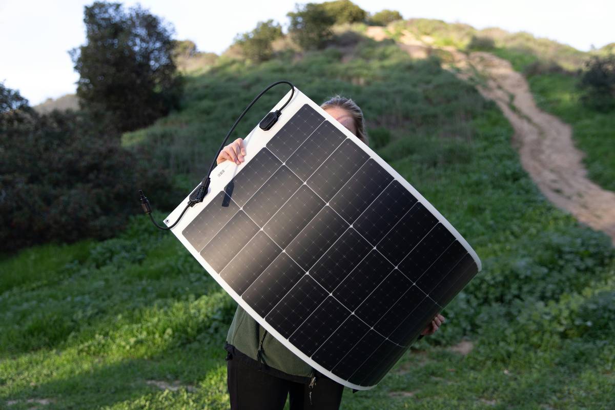 mobile solar panels for rv mounted on rooftop with portable suitcase-style panel beside an RV in desert setting